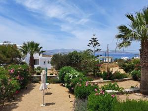 a garden with flowers and palm trees and the ocean at Our dream, seaview, near the beach in Stelida