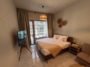 a bedroom with a bed and a tv and a couch at The Chic Retreat, Stylish Studio Close to Yas & Airport in Abu Dhabi +23 photos