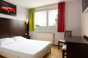 a hotel room with a bed and a desk and window at Enzo Hotels Bulgneville Relais Routier in Bulgnéville