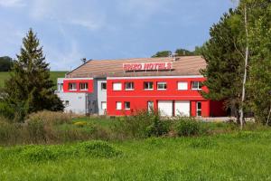 a red building with a sign on top of it at Enzo Hotels Bulgneville Relais Routier in Bulgnéville