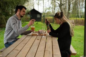 a man and woman sitting at a picnic table drinking wine at La Pierraille in Froid-Chapelle