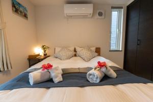 a bedroom with a bed with towels and flowers on it at Comfort Villa OKINAWA in Yabu