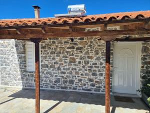 a wooden pergola in front of a stone building at Dragonera Traditional House in Episkopí