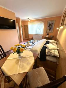 a bedroom with a bed and a table with a vase of flowers at Suita - dvojposteľová izba in Veľká Lomnica