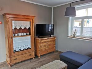 a living room with a television and a wooden cabinet at Tante Käthes Ferienhaus - FeWo ANNA in Rammenau