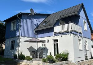 a blue and white house with an umbrella at Tante Käthes Ferienhaus - FeWo ANNA in Rammenau