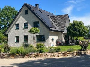 a house with a black roof and a stone wall at Relax und Wellness Landhaus in Mettingen
