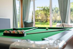 a pool table with balls and bats on it at Stunning Countryside Home in Surrey by 53 Degrees Property, Ideal for Family Getaways, Private Tennis Court! in Hascombe