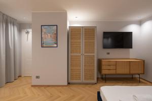 ein Schlafzimmer mit Kleiderschrank und einem Fernseher an der Wand in der Unterkunft 23 Suites in Triest