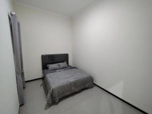BAROKAH Cordoba Homestay 1 Rumah dgn 3 Kamar في Tlekung: غرفة صغيرة مع سرير في جدار أبيض