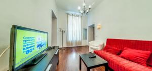 sala de estar con sofá rojo y TV de pantalla plana en Piterstay Apartments - Saint Petersburg, en San Petersburgo