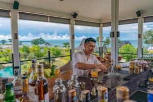a man preparing a drink at a bar at a resort at Anantara Desaru Coast Resort & Villas in Desaru