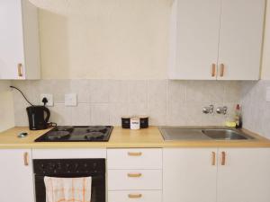 La cuisine est équipée de placards blancs, d'une cuisinière et d'un évier. dans l'établissement Hatfield Grosvenor Private Apartments 18, à Pretoria