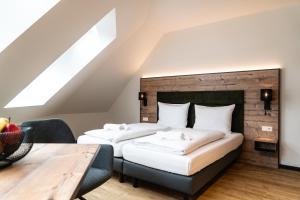 two beds in a attic bedroom with a wooden wall at SEKRA Stadthotel in Heidenheim an der Brenz