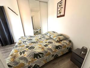 a bedroom with a bed with a floral bedspread at La sauvagine in Soustons