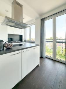CityLoft - Augsburger Innenstadt-Bismarckviertel - kostenloser Tiefgaragenstellplatz في اوغسبورغ: مطبخ مع دواليب بيضاء ونافذة كبيرة