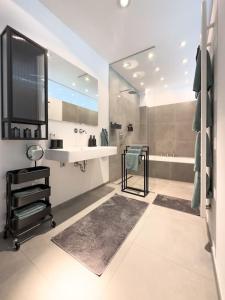 CityLoft - Augsburger Innenstadt-Bismarckviertel - kostenloser Tiefgaragenstellplatz في اوغسبورغ: حمام مع حوض و مرآة و حوض استحمام