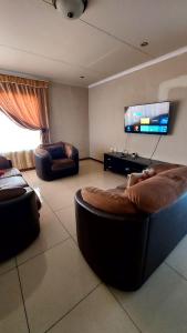 Una sala de estar con dos sofás y un televisor de pantalla plana. en Nelspruit holiday house, en Mataffin