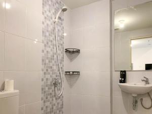 a white bathroom with a shower and a sink at Warm and Cozy Living 2BR Tokyo Riverside PIK 2 Apartment By Travelio in Rawalembang +27 photos