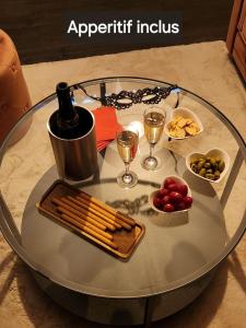 a glass table with a tray of food and glasses of wine at Love Room l'Audacieuse in Saint-Quentin