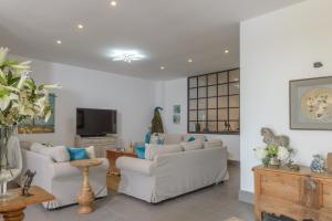 sala de estar con 2 sofás blancos y TV en Villa Bella Vida, en Benalup-Casas Viejas