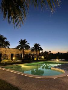 a swimming pool at night with palm trees and a building at Agriturismo San Raphael in Capaccio-Paestum