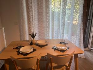une table en bois avec des assiettes et des bols dans l'établissement Appartement Cormeilles, à Cormeilles-en-Parisis