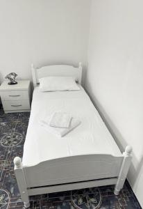 a white bed in a white room with a night stand at Villa Agos in Shkodër