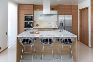 eine Küche mit einer großen Insel mit drei Barhockern in der Unterkunft Luxury Riverside Villa w Magnificent River Views in Rovaniemi