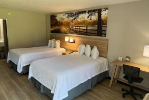 a hotel room with two beds and a desk at Days Inn by Wyndham Crystal River in Crystal River