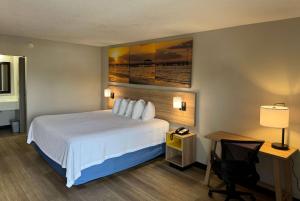 a hotel room with a bed and a desk with a lamp at Days Inn by Wyndham Crystal River in Crystal River