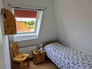 ヴィーク・アウフ・リューゲンにあるFerienwohnung An de Waterkant Wiekのベッドと椅子と窓のある寝室