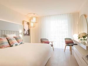 a bedroom with a white bed and a window at Croisette Beach Hotel Cannes - MGallery Collection in Cannes