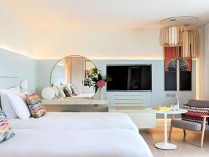 a hotel room with two beds and a mirror at Croisette Beach Hotel Cannes - MGallery Collection in Cannes