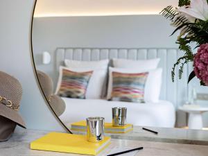 a mirror on a table next to a bed with pillows at Croisette Beach Hotel Cannes - MGallery Collection in Cannes