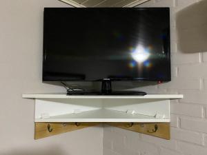 a flat screen tv on a shelf on a wall at Pousada dos Pássaros in Gramado