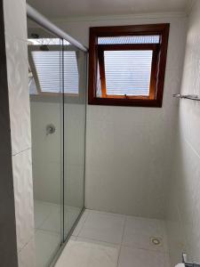 a bathroom with a glass shower with a window at Pousada dos Pássaros in Gramado