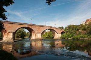 eine Brücke über einen Fluss mit Reflexionen im Wasser in der Unterkunft Le 20 in Cintegabelle