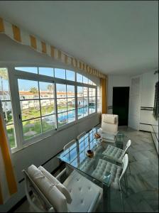 a living room with a glass table and white chairs at Apto Laguna con piscina in El Portil