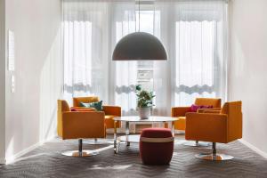 a living room with orange chairs and a table at Best Western Plus Park City Solna in Solna