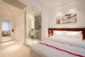a bedroom with a large white bed and a glass walk in shower at Ruby Marie Hotel Vienna in Vienna