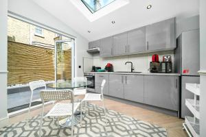 a kitchen with a glass table and white chairs at Nine Elms City Suites in London