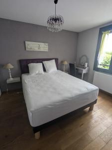 a bedroom with a large white bed with a chandelier at Teresa Beauté - grande maison 4 chambres proche La Rochelle Ile de Ré avec piscine in Périgny