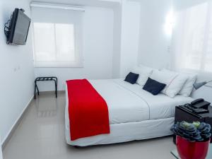 a white bedroom with a red and white bed and a tv at Zalmedina Hotel in Cartagena de Indias