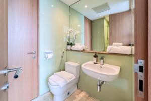 a bathroom with a sink and a toilet and a mirror at Soho Suites KLCC by Leala in Kuala Lumpur +17 photos