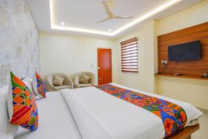 a bedroom with a large bed and a flat screen tv at FabHotel Partha Residency - Kr puram in Bangalore