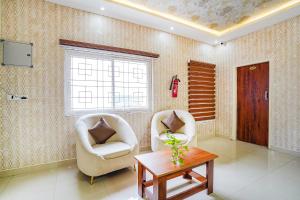 a living room with two chairs and a table at FabHotel Partha Residency - Kr puram in Bangalore