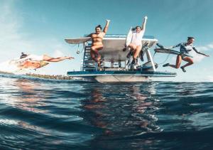 a group of people jumping off a boat in the water at Surf Trip Maldives in Thulusdhoo