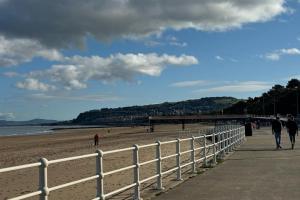Menschen, die am Strand neben einem Zaun spazieren gehen in der Unterkunft Central Colwyn Bay 2nd Floor Flat 3 in Colwyn Bay