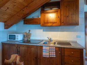 a kitchen with wooden cabinets and a sink and a microwave at Apartment Grand Sarriod-2 by Interhome in Saint Nicolas +14 photos